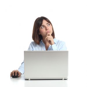 Pensive woman thinking while is using a laptop and looking sideways isolated on a white background